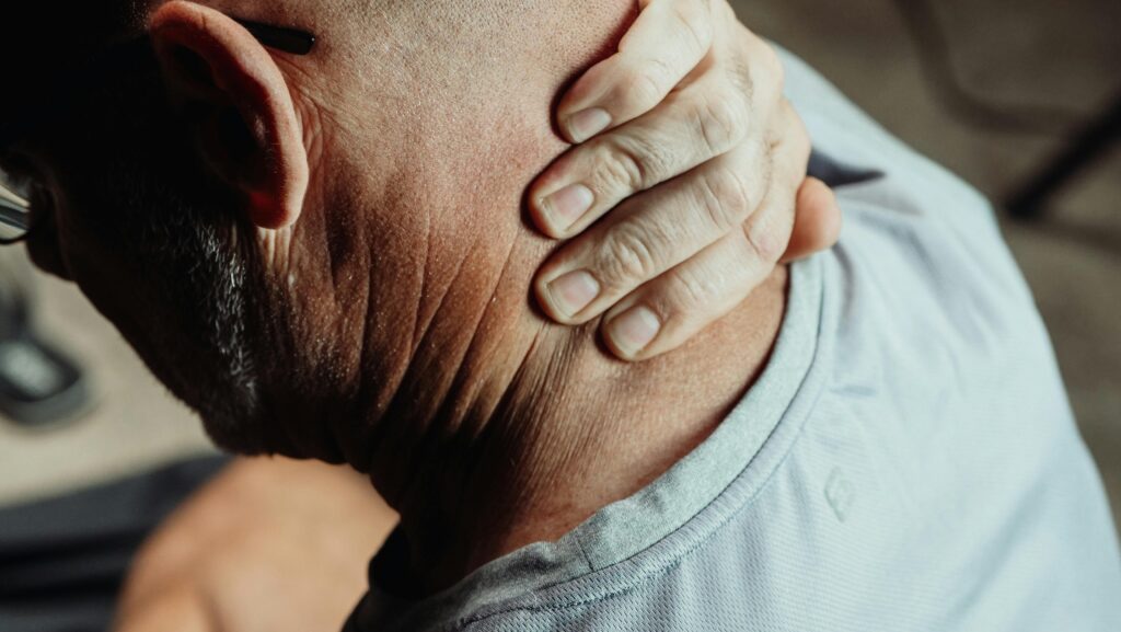 Man with neck pain holding his neck in discomfort, conveying tension or stress.